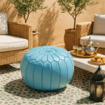 Round leather floor ottoman pouf in sky blue on outdoor patio, Moroccan-style embroidered design accent piece
