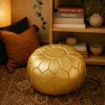 Round gold leather floor ottoman with star embroidery on patterned rug in cozy bohemian setting