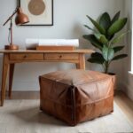 Square leather ottoman as desk footrest in modern home office with wooden furniture and plants