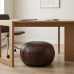 A minimalist home office featuring a Chocolate Brown Ottoman tucked neatly under a light oak desk as a versatile seating option.