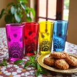 Colored tea cups with pastries and greenery
