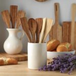 Handcrafted lemon wood kitchenware 12" utensils in ceramic holder with bread and lavender on wooden surface