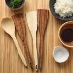 Natural grain lemon wood kitchenware 12" spatulas and spoons arranged flat with soy sauce and rice bowls