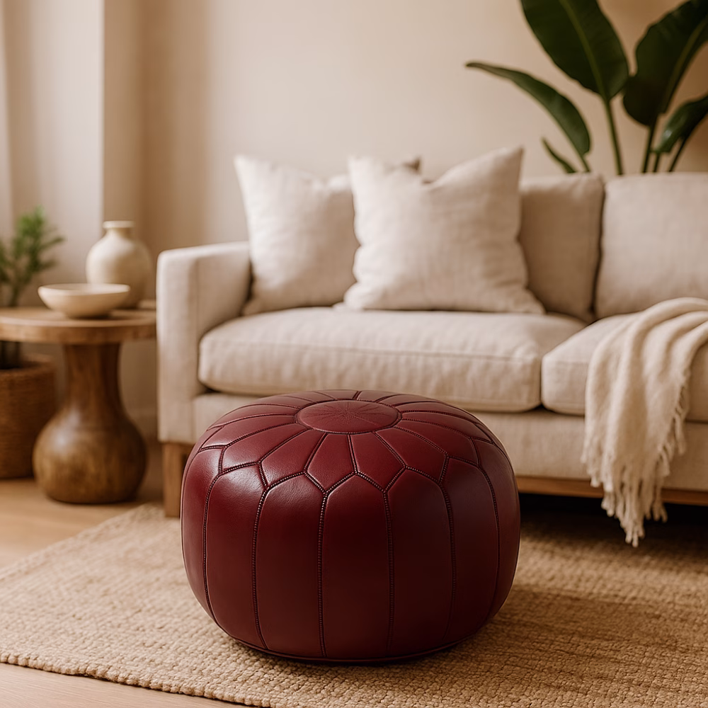 Deep Red Leather Pouf Round accenting a modern living room with beige sofa and neutral decor.