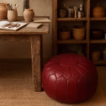 Deep Red Leather Pouf Round in artisan studio setting with pottery and wooden desk.