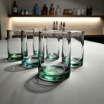 Trio of aqua and green handblown wine glasses with lemon slices and water