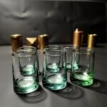 Four blue and green handblown wine glasses arranged on a sunlit stone patio