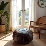 Classic leather ottoman pouf in sunlit room with rattan chair