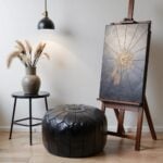 Black leather floor ottoman in studio setting - artisan crafted round pouf with geometric star pattern