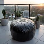 Black leather floor ottoman on rooftop terrace - durable handcrafted pouf with decorative stitching
