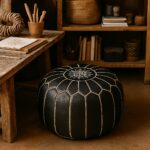 Moroccan black leather floor ottoman with white embroidered star pattern next to natural wood furniture