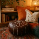 Dark brown leather round pouf with Moroccan embroidery in a cozy bohemian reading corner with colorful rug