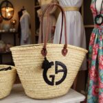 Handwoven designer straw tote bag with black tassel charm in boutique display setting