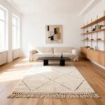 Cream Beni Ourain rug in minimalist living room with natural wood shelving and beige sofa on hardwood floor