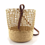 Handwoven straw backpack with leather details on white background