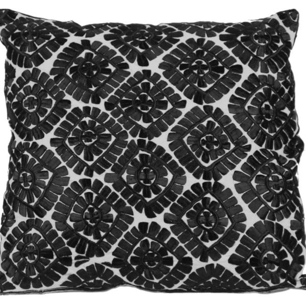 Close-up of black geometric pillow covers with raised leather floral appliqué detail and stitching
