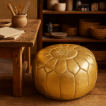 Handcrafted gold leather floor ottoman with geometric stitching near wooden table in rustic interior