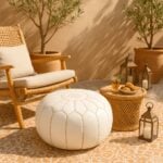 White leather round ottoman pouf on Moroccan tile patio with rattan chair and Mediterranean garden setting