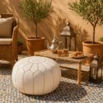 White leather round ottoman pouf on mosaic terrace with Moroccan tea set and olive trees in background