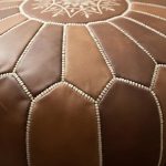 Close-up detail of the varied brown and caramel panels and light-colored stitching on the Leather Round Ottoman.