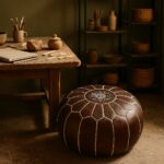 Dark brown leather round pouf with white embroidered star pattern in an artisan pottery studio workspace