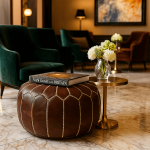 Luxury leather floor ottoman pouf in elegant living room with green velvet chair and gold accents