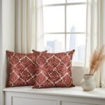 Handcrafted geometric pillow covers featuring terracotta leather florals on white bench near window