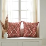 Set of 2 geometric pillow covers in terracotta leather appliqué on cream sofa with monstera plant