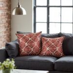 Terracotta geometric pillow covers with dimensional leather appliqué on dark gray modern sofa