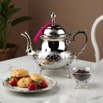 Traditional silver teapot with fresh berries and pastries