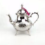 Silver-plated engraved teapot with intricate geometric patterns and footed base design showcasing elegant craftsmanship