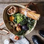 Moroccan straw basket bag with herringbone weave filled with fresh market produce on rustic wood