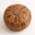 Overhead view of handcrafted natural leather pouf with white stitching