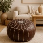 Dark brown leather round pouf with star embroidery in a minimalist living room beside a white sofa