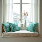 Teal floral pillow covers on window seat with cream cushion and pampas grass decor