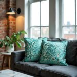 Teal floral pillow covers on dark gray sofa in industrial loft setting with brick wall