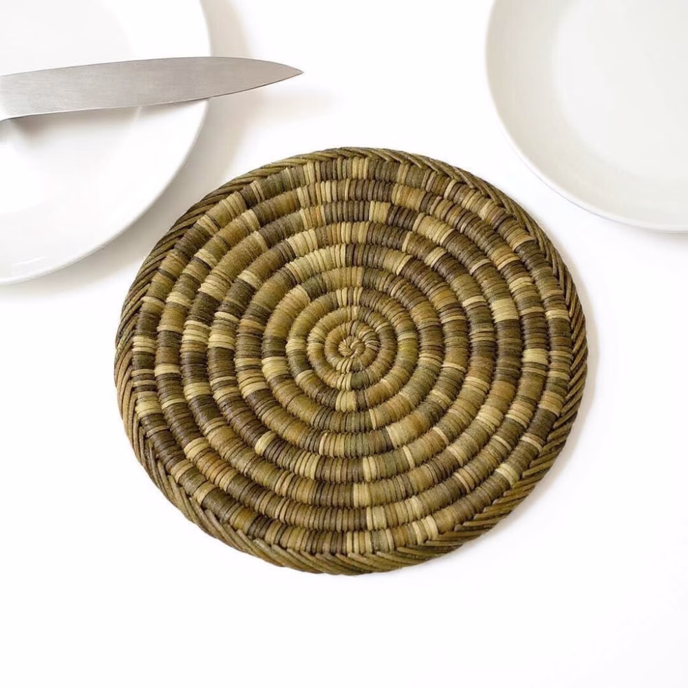 Single straw placemat styled as a charger beneath minimalist white crockery
