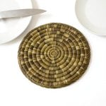 Detailed view of hand-woven straw kitchenware placemat showing tight spiral coil weaving pattern and texture