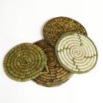 Stack of four round Moroccan straw placemats showing varied earthy shades