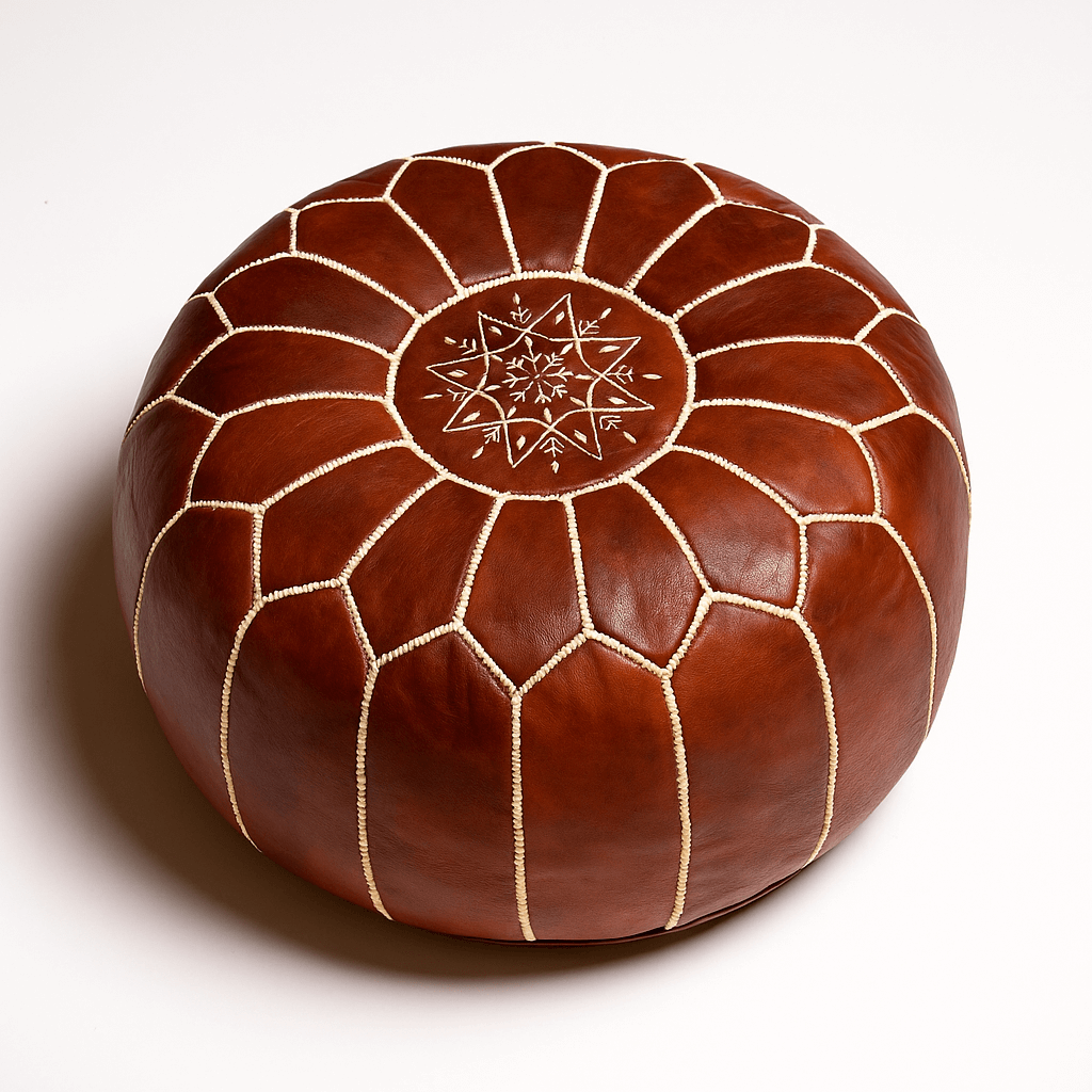 Studio shot of a leather pouf brown with detailed embroidery, highlighting the artisanal quality of Moroccan craftsmanship. Handcrafted brown leather floor ottoman with white embroidered star pattern and geometric stitching details