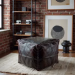 Square ottoman pouf against exposed brick wall