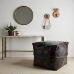 Square leather floor ottoman on area rug in bright living room with beige sofa and plants