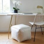 White square leather pouf 16 inch ottoman under minimalist desk with gold legs in bright workspace
