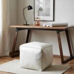Handcrafted white square leather pouf with topstitching under modern wood and metal desk as footrest