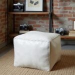 White square leather pouf 16 inch floor ottoman on beige rug in industrial loft with exposed brick