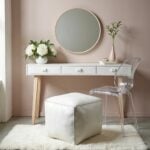 Modern white square leather pouf footrest beneath contemporary desk with gold legs and brass lamp