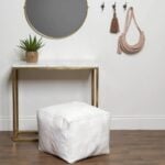 Handcrafted white square leather pouf with contrast stitching under wooden desk with copper accents
