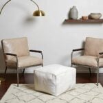 White square leather pouf 16 inch cube ottoman under gold console table in modern minimalist entryway