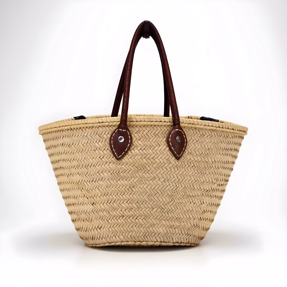 Natural straw bag with leather handles on white background