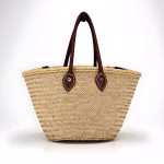 Natural straw bag with leather handles on white background